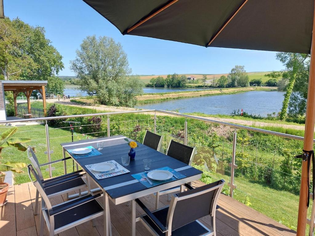 einen Tisch und Stühle auf einer Terrasse mit Flussblick in der Unterkunft maison caroline bairon in Le Chesne