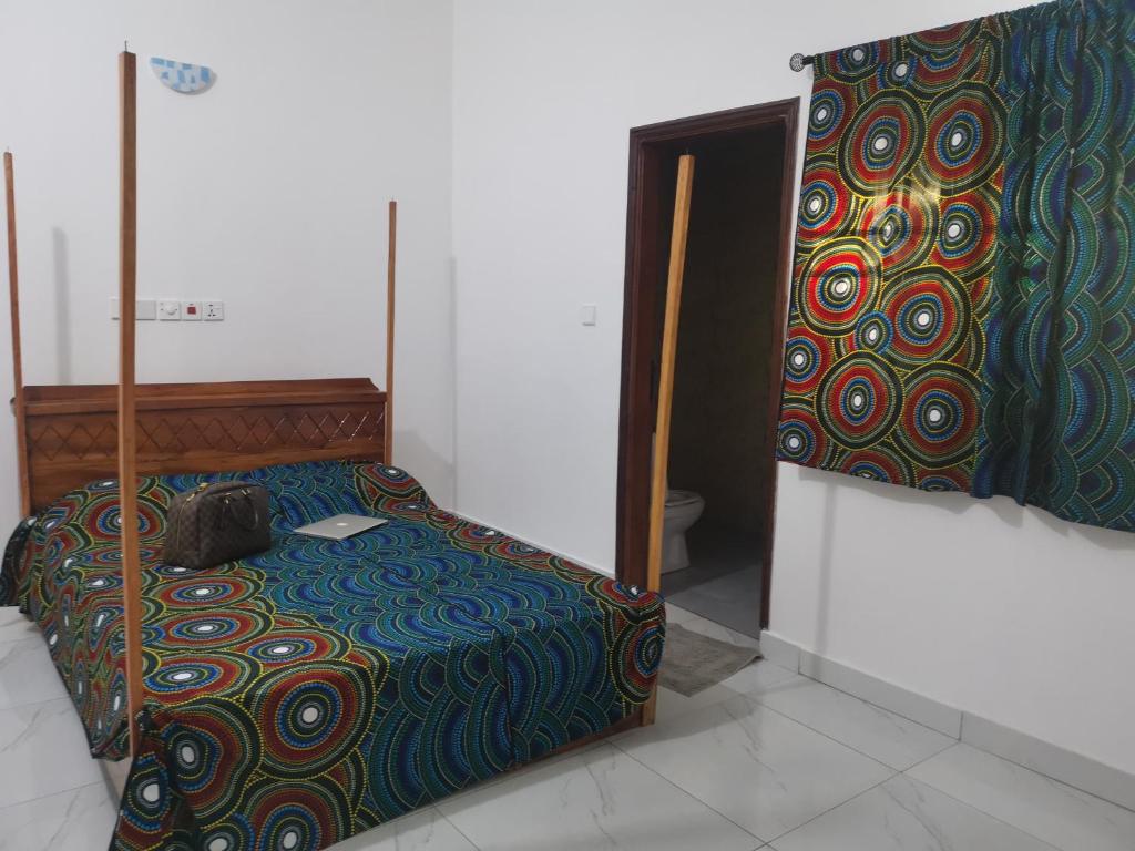 um quarto com uma cama com um cobertor colorido em Le Havre Béninois em Cotonou