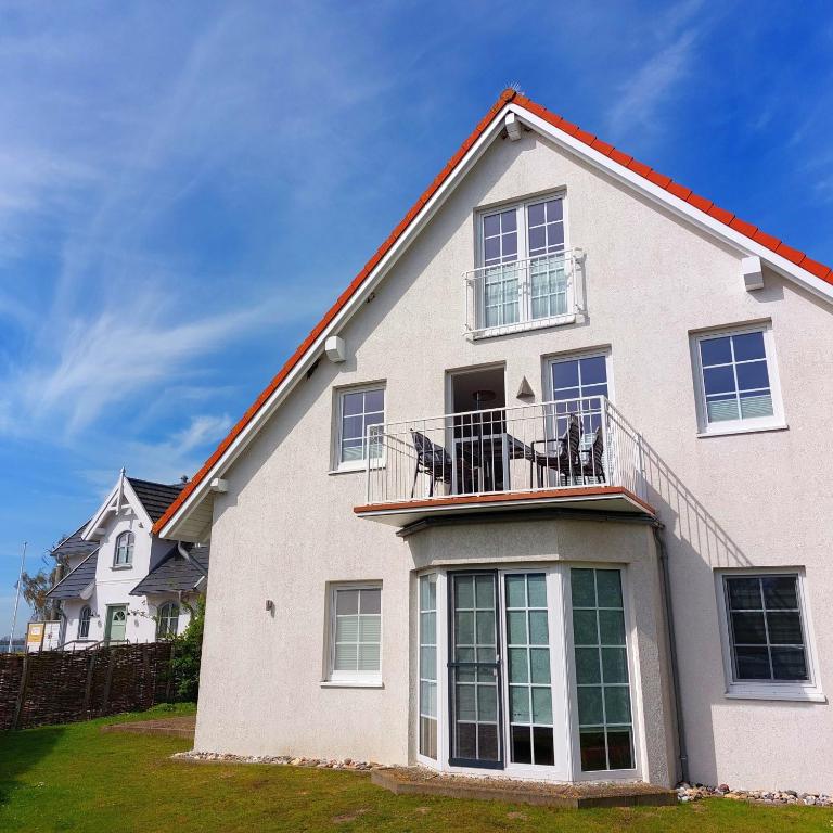 ein weißes Haus mit Stühlen auf dem Balkon in der Unterkunft Mina in Fehmarn