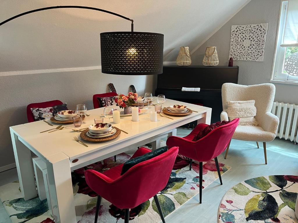a dining room with a white table and red chairs at Sweet Little Home Mimi in Berlin