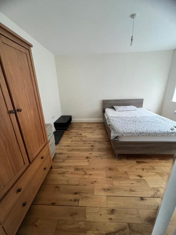 een slaapkamer met een bed en een houten kast bij Beautiful Double Room in Hornchurch