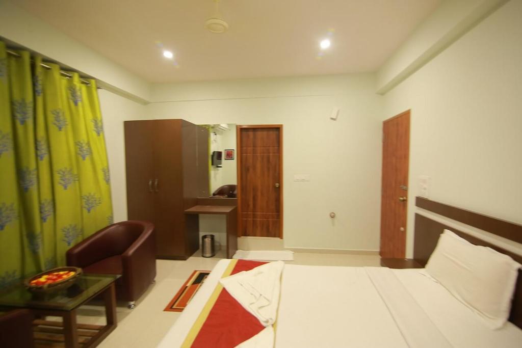 Pokój z łóżkiem, krzesłem i stołem w obiekcie golden residency Mysore w mieście Mysuru
