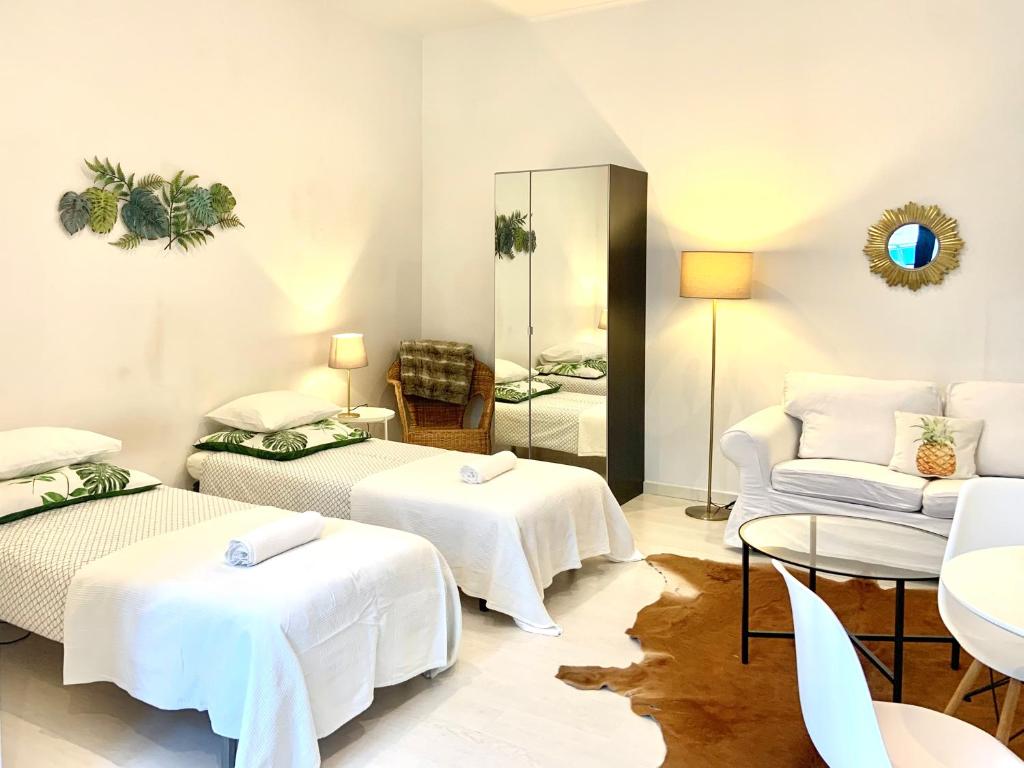 Cette chambre comprend 3 lits, un canapé et un miroir. dans l'établissement Alcântara Studio 15, à Lisbonne
