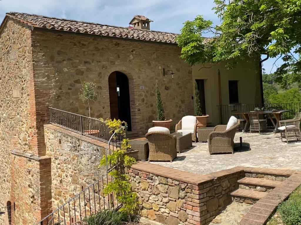 een terras met stoelen en een stenen muur bij Villa Montebella in Nottola