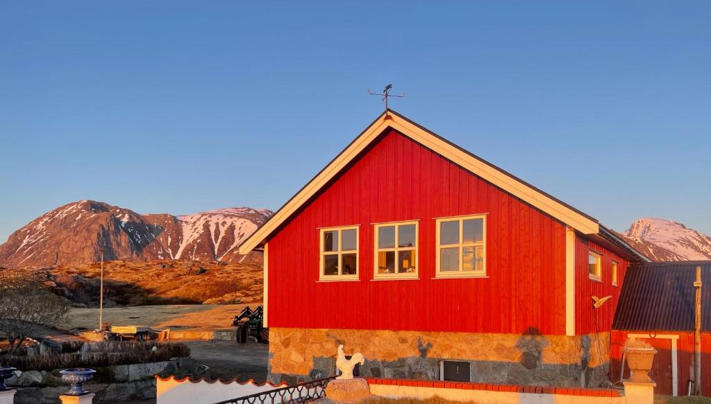 a red house with mountains in the background at Lofoten Ocean View - Sandøy Gård in Sand