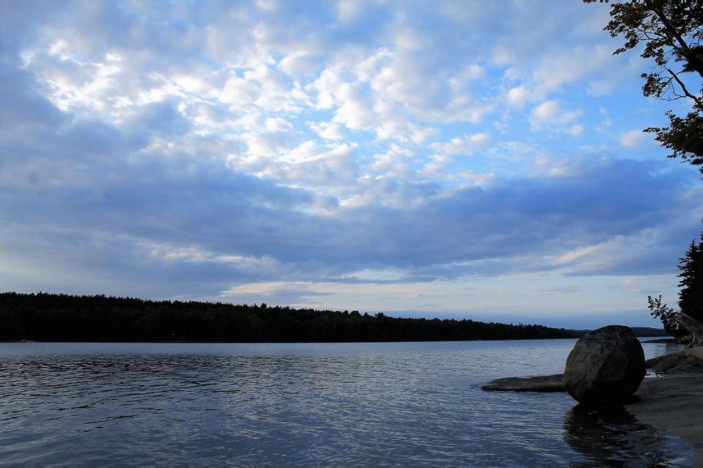 una gran roca sentada en la orilla de un lago en Sunset Cove Cottage private beach en Prospect Harbor