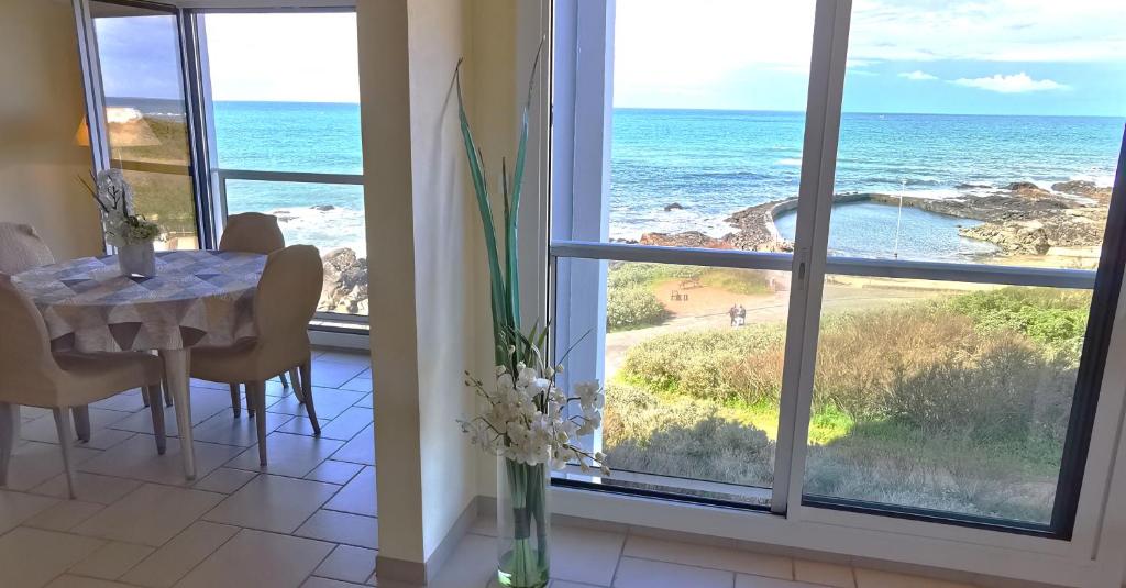 une salle à manger avec une table et une vue sur l'océan dans l'établissement Le Grand Panoramique - Face Mer, à Les Sables-dʼOlonne