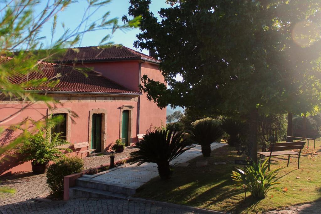 una casa rosa con árboles y plantas delante de ella en Quinta de Baixo, en Vila Marim