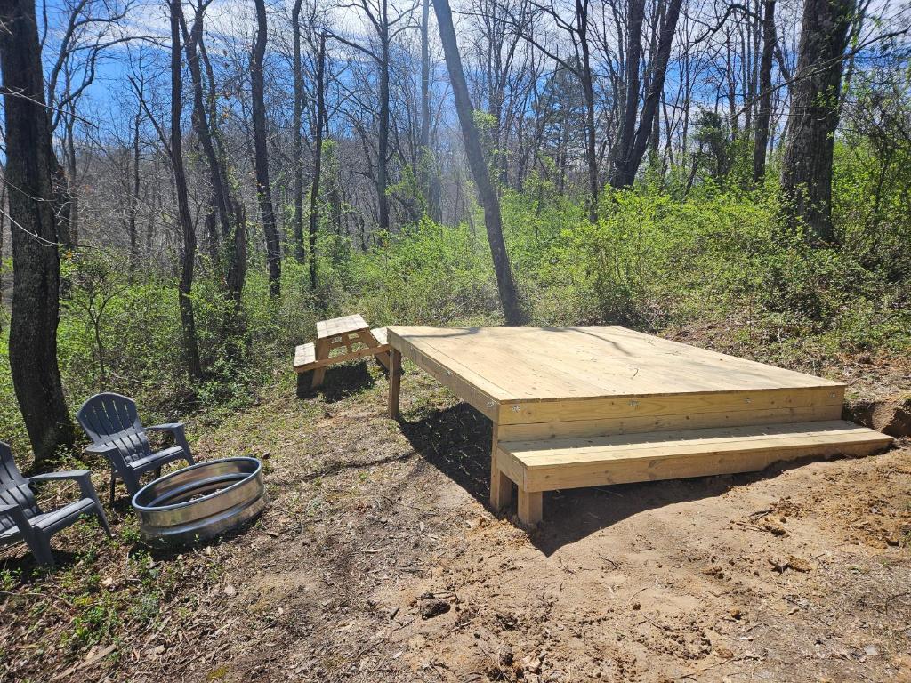 a wooden picnic table and two chairs in the woods at Black Oak Campsite at Hocking Vacations Campsites - Tent not Included in Logan