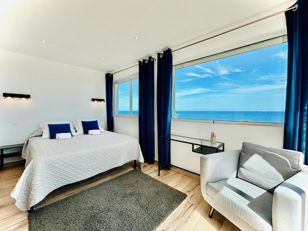 - une chambre avec un lit, une chaise et une grande fenêtre dans l'établissement Residence Canella, à Sari-Solenzara