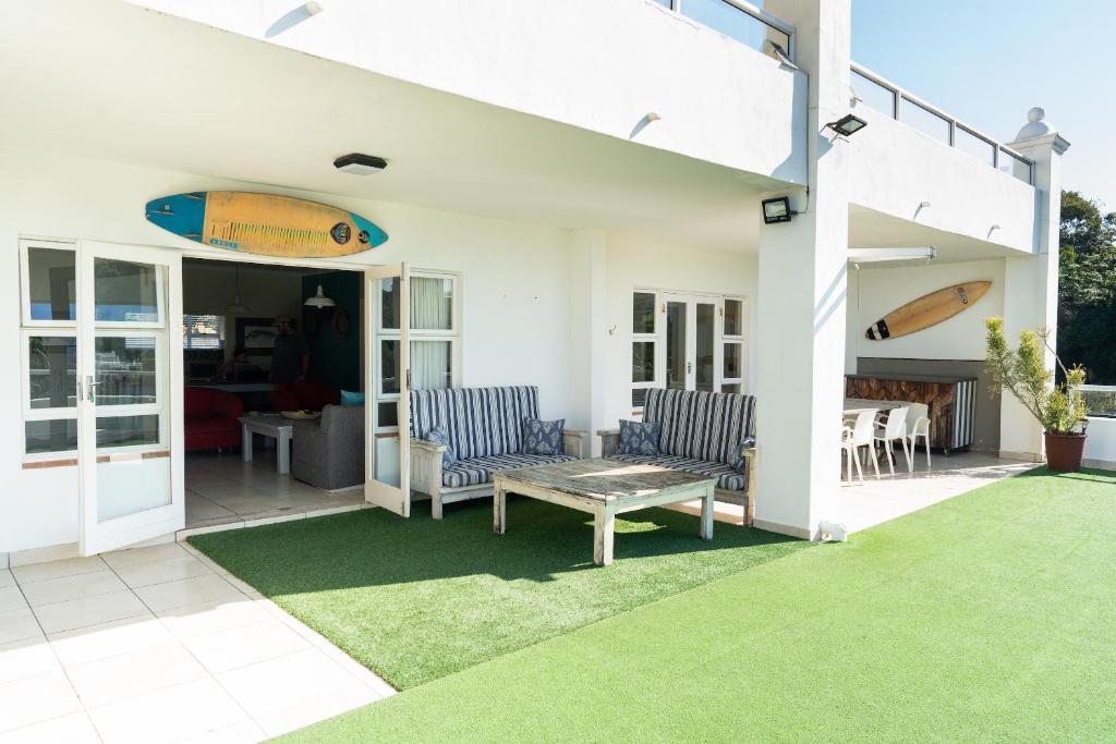 eine Terrasse mit 2 Stühlen und einem Tisch mit Surfbrett in der Unterkunft Villa 43, The Estuary Country Estate, Port Edward, KZN South Coast in Port Edward