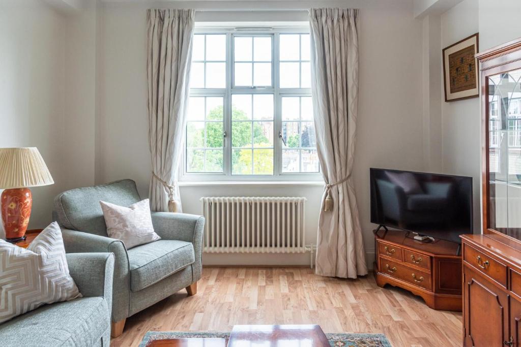 ein Wohnzimmer mit einem Sofa und einem TV in der Unterkunft Chestnut Blossom - 1 Bedroom in Kensington in London