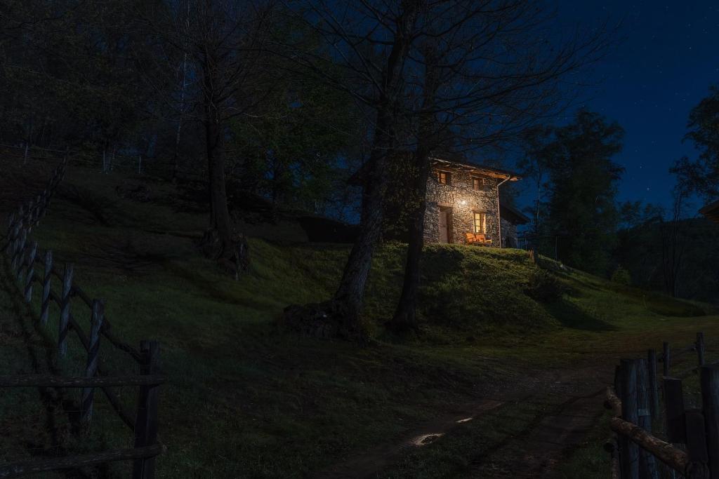 une maison éclairée sur une colline la nuit dans l'établissement Agriturismo l'Arbo, à Andorno Micca