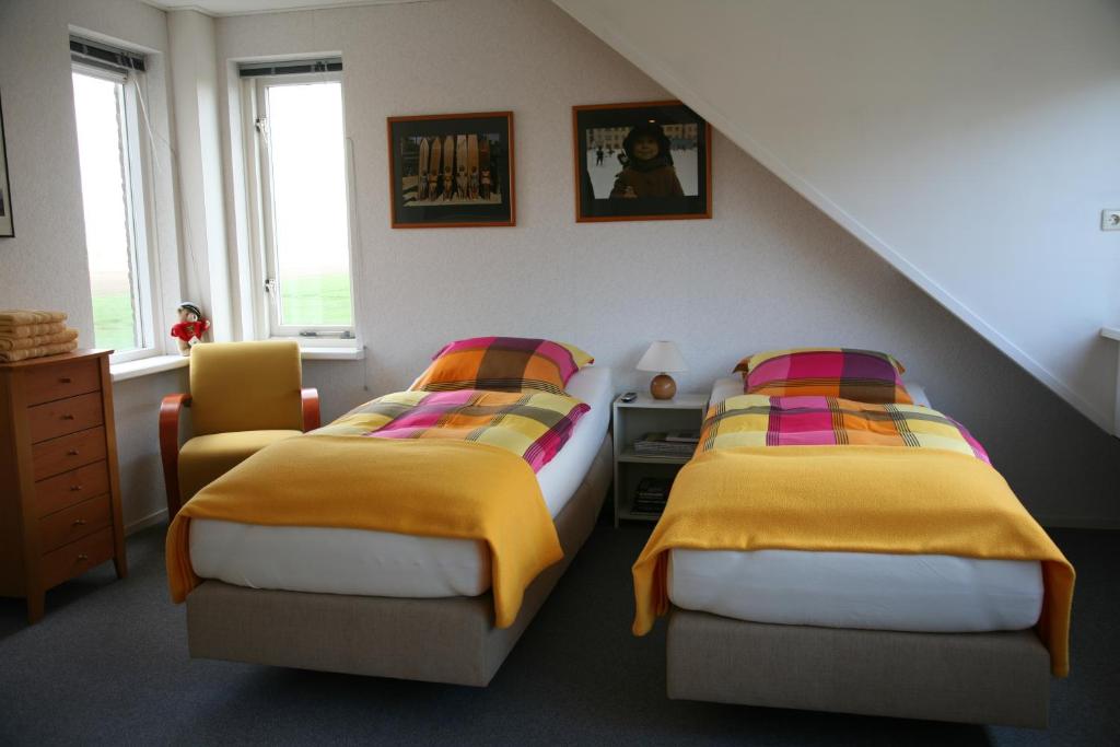 een slaapkamer met twee bedden met gele en kleurrijke dekens bij B&B Korendijk in Zuid-Beijerland