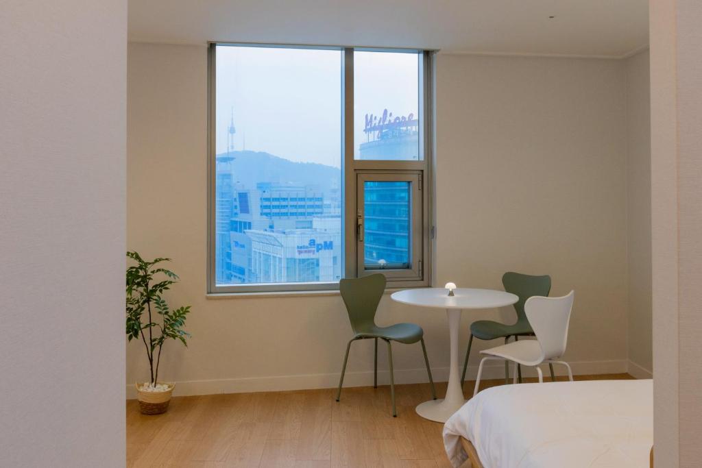 ソウルにある"GRAND OPENED" Maxtyle Guesthouse Dongdaemunのテーブルと椅子、窓が備わる客室です。