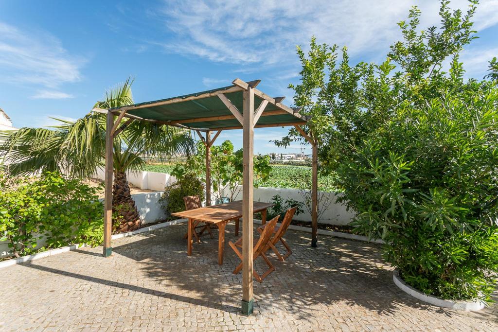 einen Holztisch und Stühle unter einem Sonnenschirm in der Unterkunft BLife Salinya private rooms in Olhão