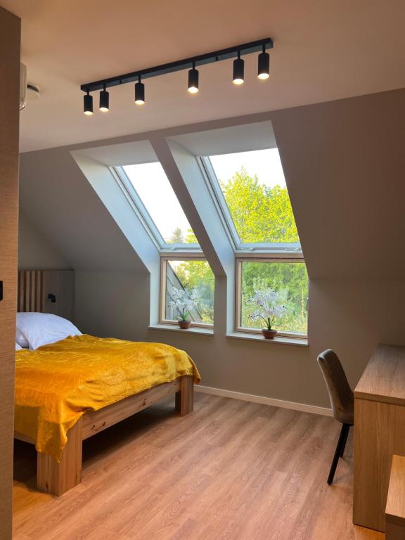 1 dormitorio con 2 ventanas y 1 cama con manta amarilla en Willa Olimpia, en Podzamcze