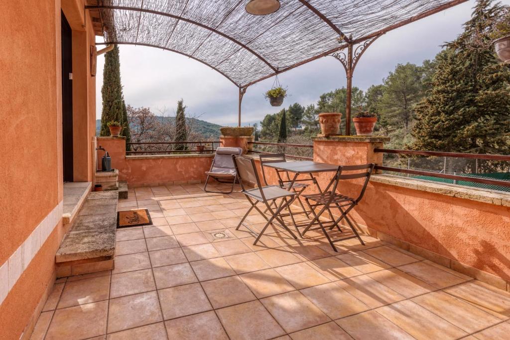 un patio avec une table et des chaises sur un balcon dans l'établissement La Maison du Chapelier, à Fontaine-de-Vaucluse