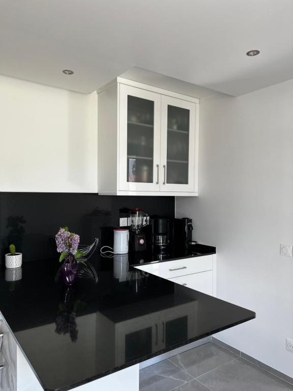 une cuisine avec des armoires blanches et un comptoir noir dans l'établissement Villa near CDG Paris aeroport, à Arnouville-lès-Gonesse