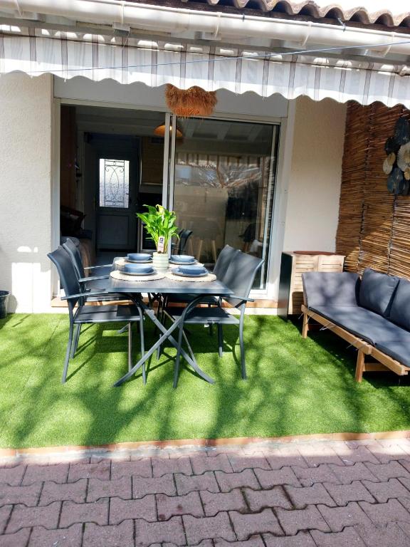 un patio avec une table et des chaises sur l'herbe dans l'établissement Casa Littoral, au Grau-dʼAgde