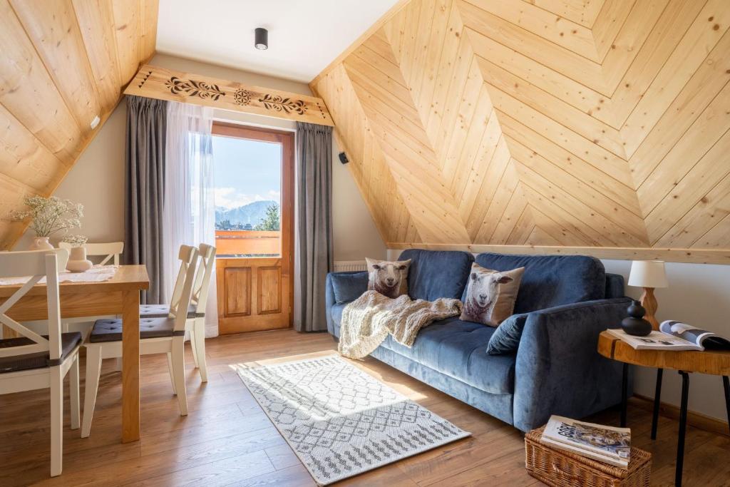un soggiorno con divano blu e soffitto in legno di U Dzikosa a Ząb