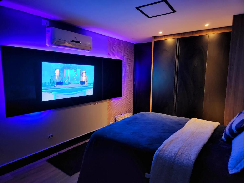 1 Schlafzimmer mit einem Bett und einem TV mit lila Lichtern in der Unterkunft Desativado in Osasco