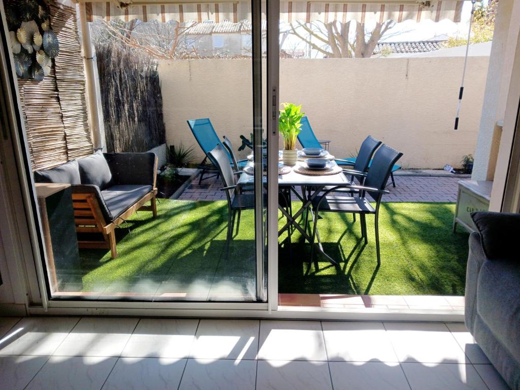 a patio with a table and chairs on the grass at Casa Littoral in Le Grau-dʼAgde