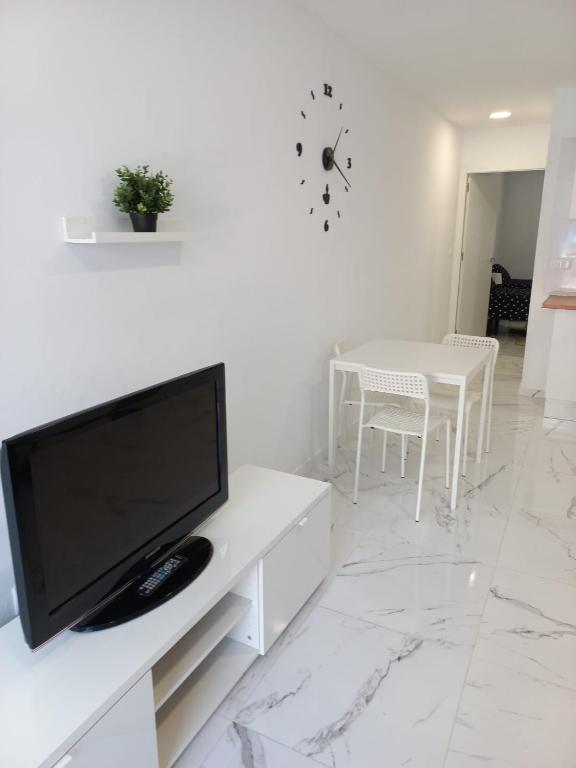 sala de estar blanca con TV y mesa en Casa de Afriquita, en Granadilla de Abona