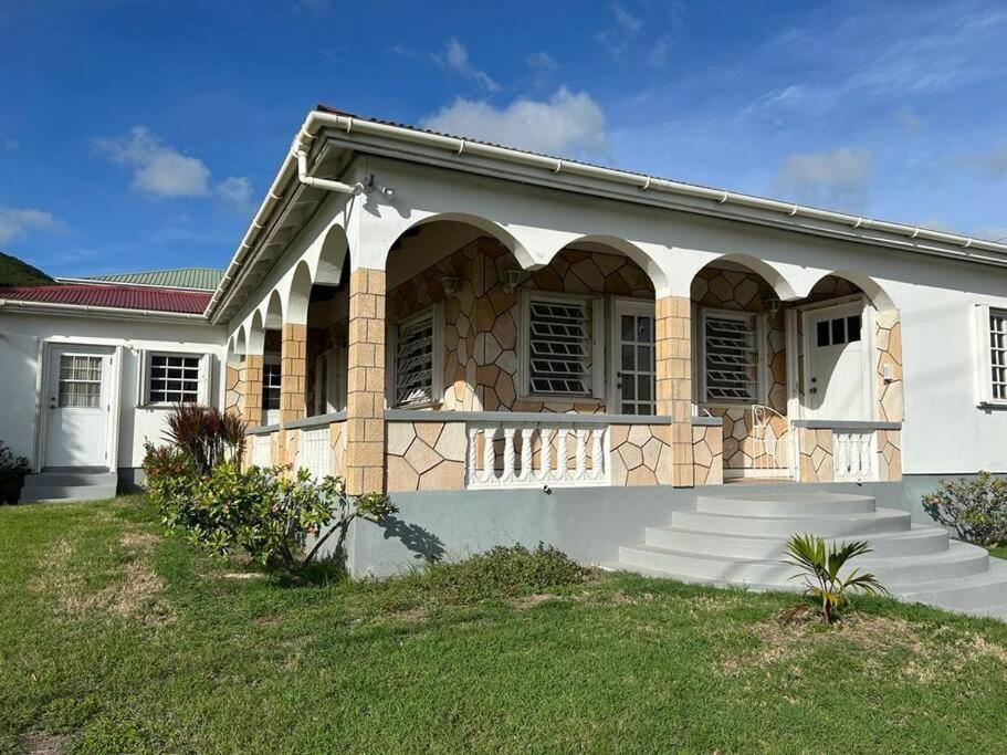 a white house with a porch and some stairs at Casa Patricia in Cades Bay