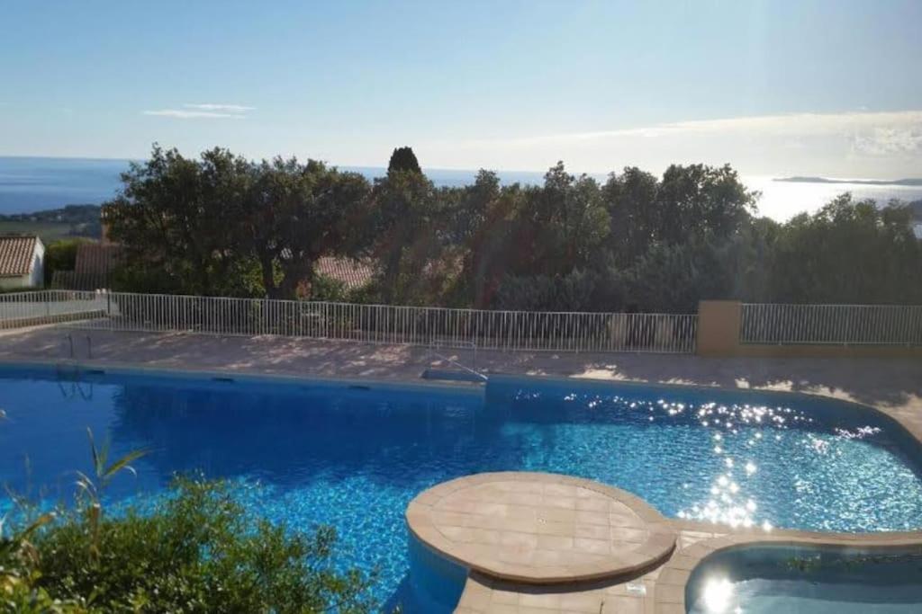 une grande piscine bleue avec une table et des chaises dans l'établissement Très joli appartement T2 40 m2 avec piscine, à La Croix-Valmer