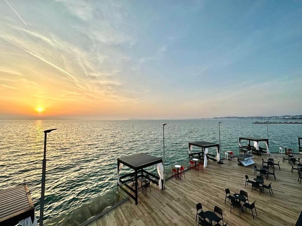 a pier with tables and chairs on the water at sunset at Holiday apartment, Qerret in Golem