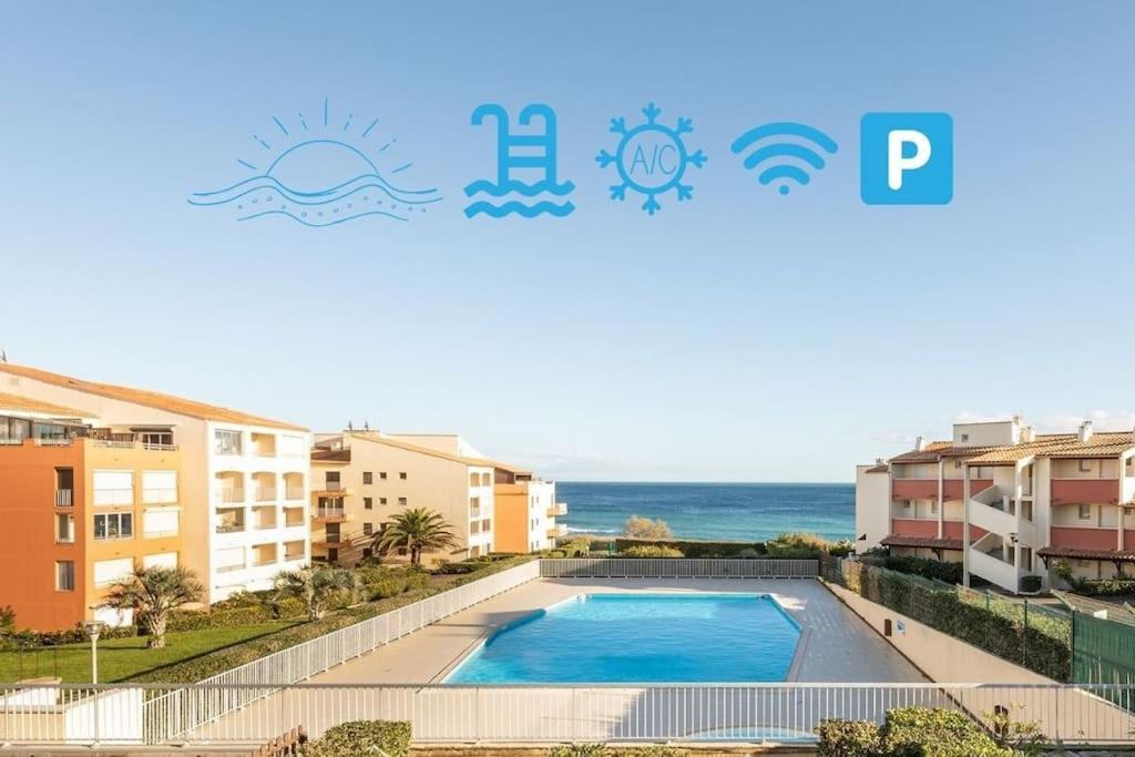 - une vue sur la piscine en face de certains bâtiments dans l'établissement Une pépite face à la mer avec accès direct plage, au Cap d'Agde