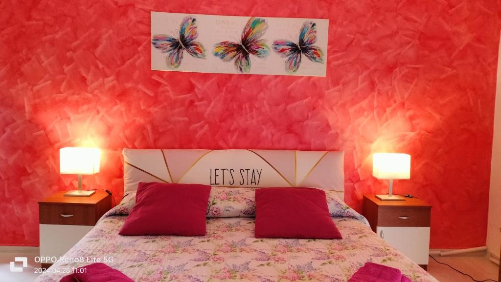 um quarto com uma cama com paredes vermelhas e 2 candeeiros em Rubino house em Lentini