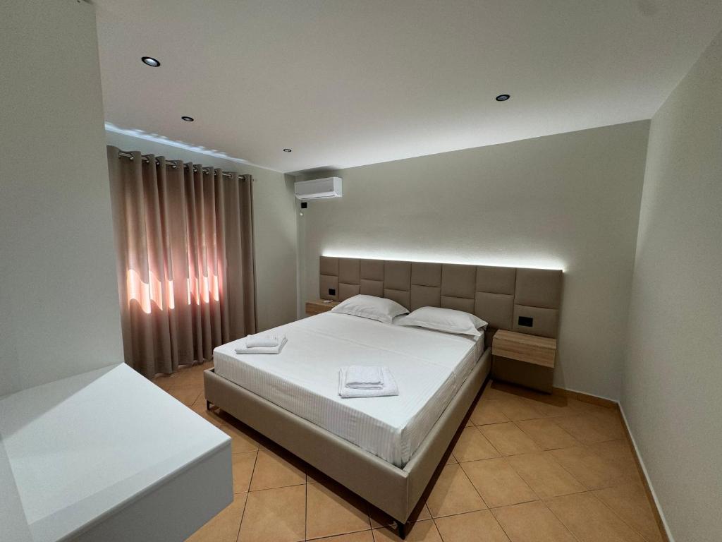 a bedroom with a white bed and a window at Garden Villa Apartments in Sarandë