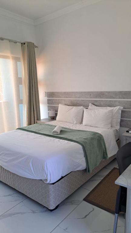 a bedroom with a large bed with a gray headboard at Onamungundo Backpackers in Walvis Bay