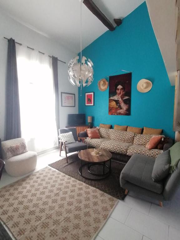 un salon avec un canapé et un mur bleu dans l'établissement Le super duplex des halles, à Sète