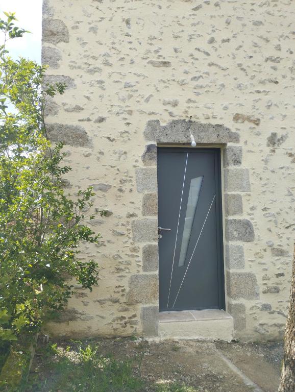 une porte sur le côté d'un bâtiment en pierre dans l'établissement Gîte des Trois Cantons, à Beaurepaire