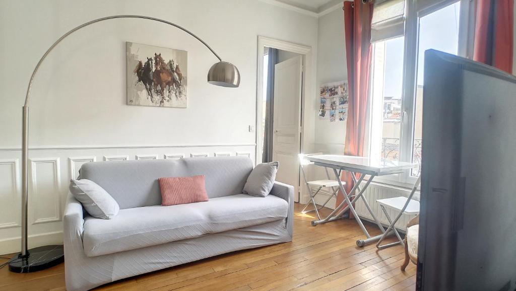un salon avec un canapé blanc et une table dans l'établissement Appartement typiquement parisien au pied du métro, à Issy-les-Moulineaux