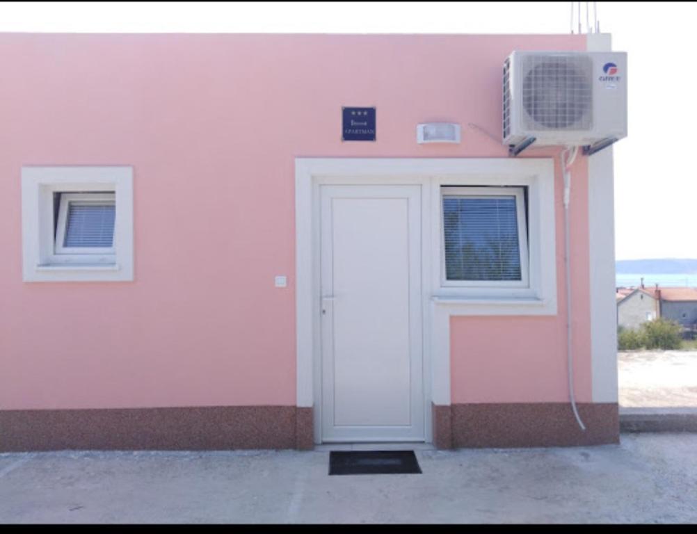 a pink building with a door and a window at ApartmanA&J1111 in Kaštela