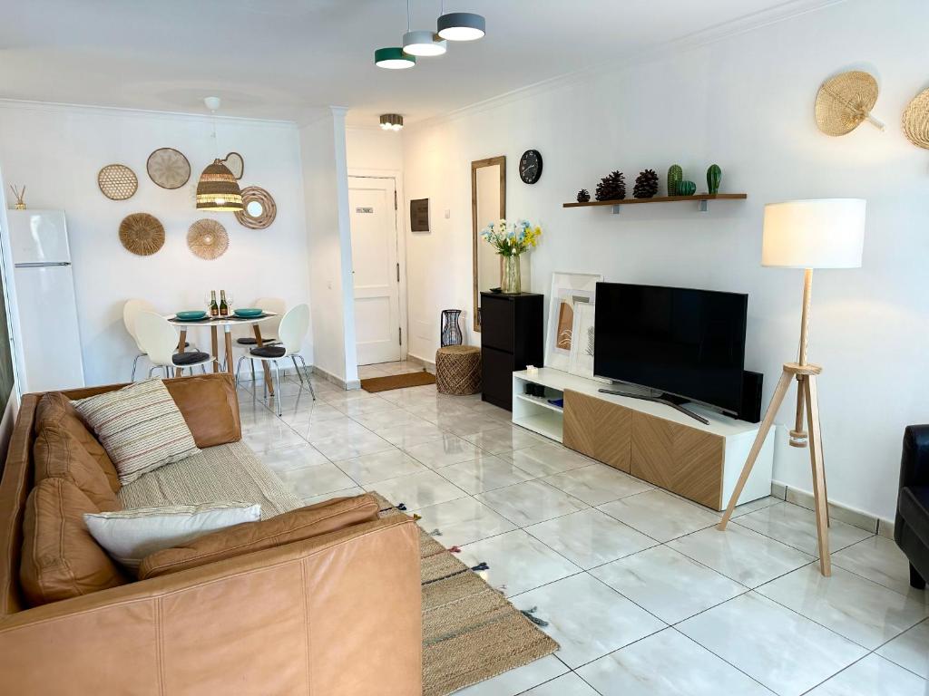 sala de estar con sofá y TV de pantalla plana en Las Olas DM cozy 2-bedrooms apartment en Maspalomas