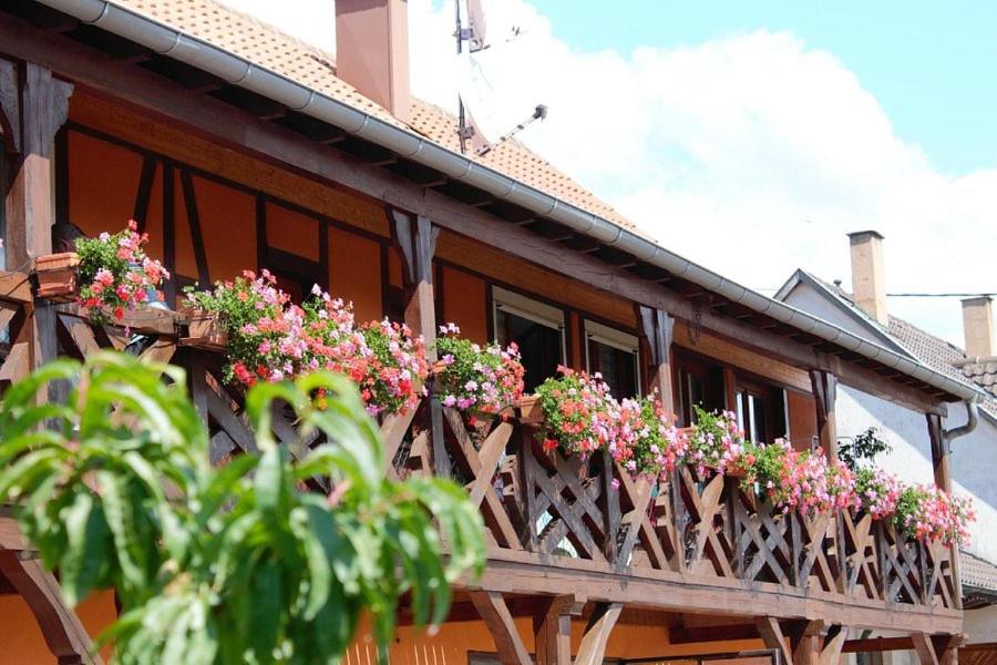 a wooden balcony with flowers on a house at Chambres d'Hôtes Arnold in Dambach-la-Ville