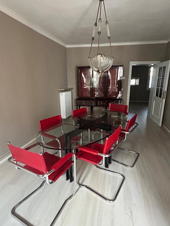 a dining room with a glass table and red chairs at HEATHER'S HOME in Bassano del Grappa