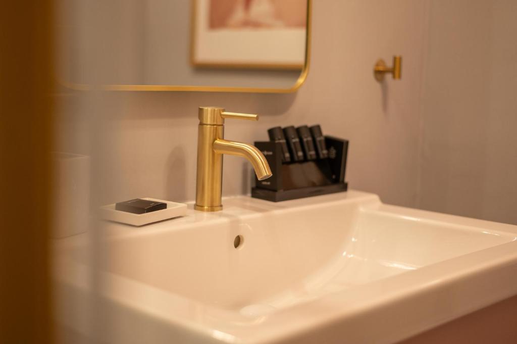 a bathroom sink with a gold faucet on it at L Suites The Writer's House in Gythio