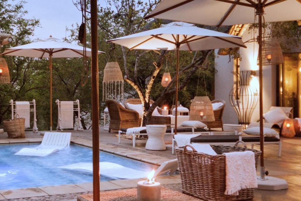 a pool with chairs and umbrellas next to at African Flair Boutique Safari Lodge in Hoedspruit