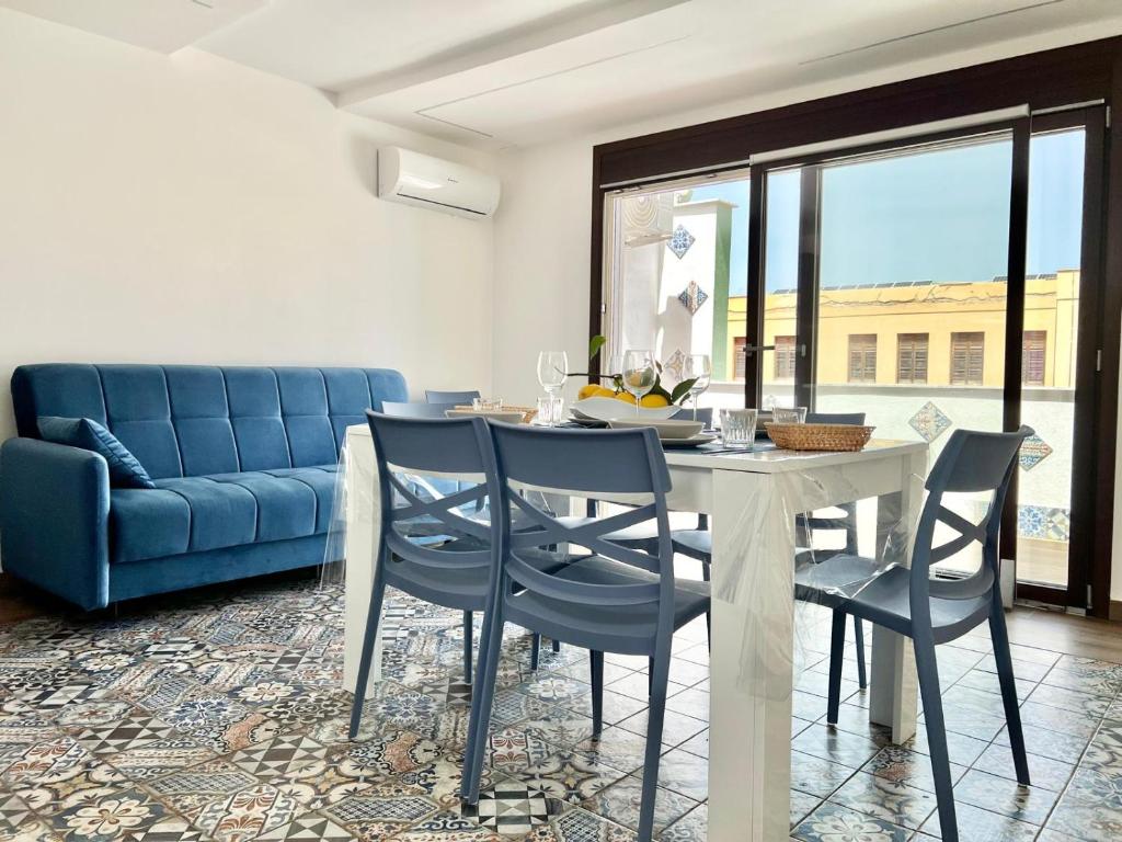 comedor con mesa y sillas y sofá azul en M'AMA apartment 2, en Ficarazzi