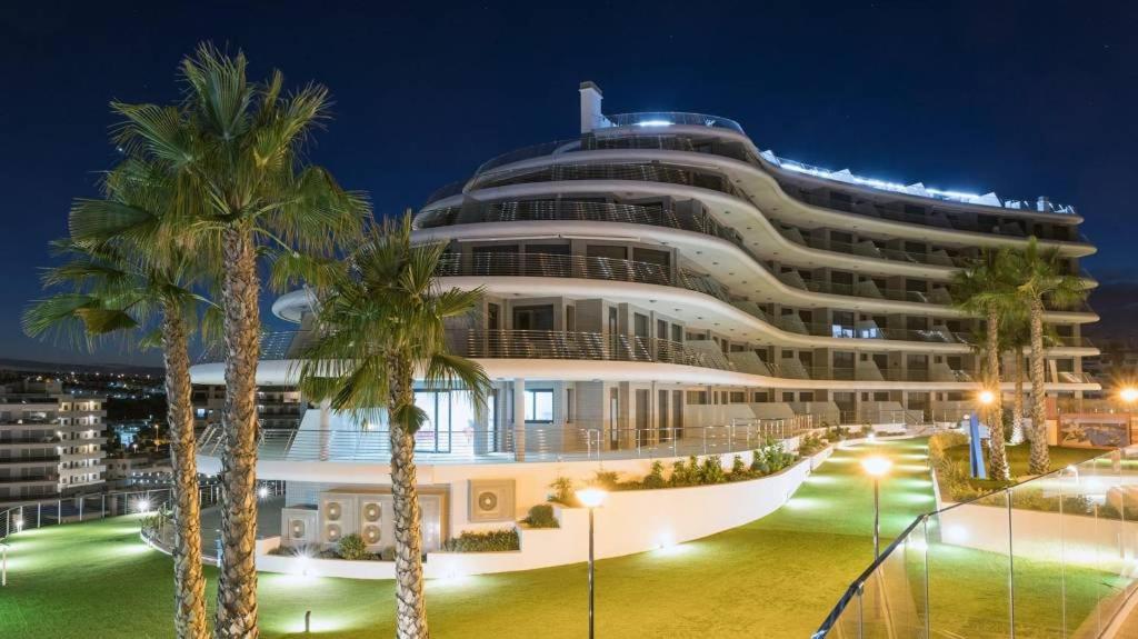 a large building with palm trees in front of it at Apartament Infinity View in Arenales del Sol