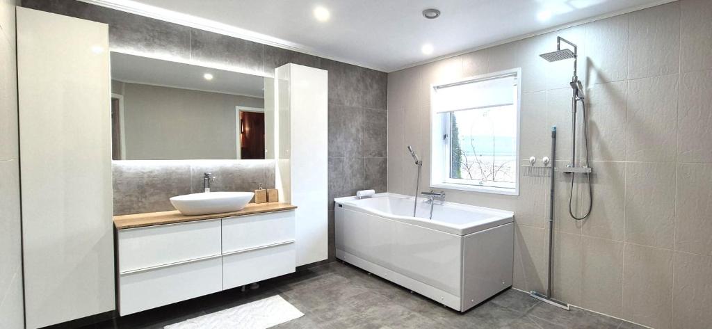 een badkamer met een bad, een wastafel en een douche bij Glomma House in Kongsvinger