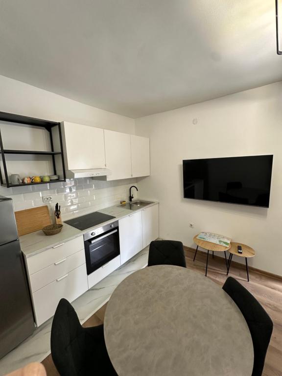 a kitchen with a table and a kitchen with a tv at Ronia apartment in Kaštela