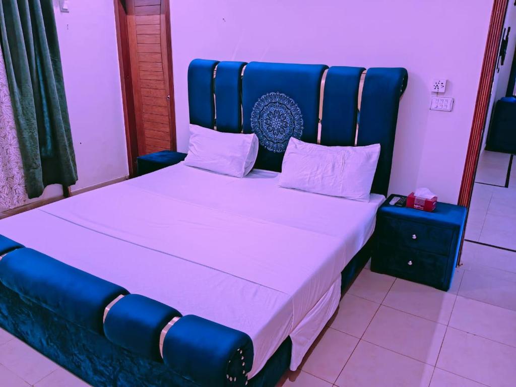- un grand lit avec une tête de lit bleue dans l'établissement Home Inn Guesthouse, à Islamabad