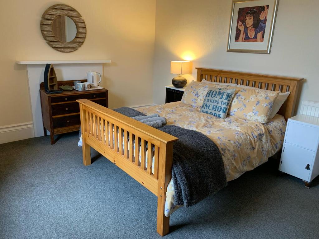 a bedroom with a bed and a night stand with a mirror at Peaceful garden view double with ensuite in house opposite beach, with access to private garden and bike store in Kent